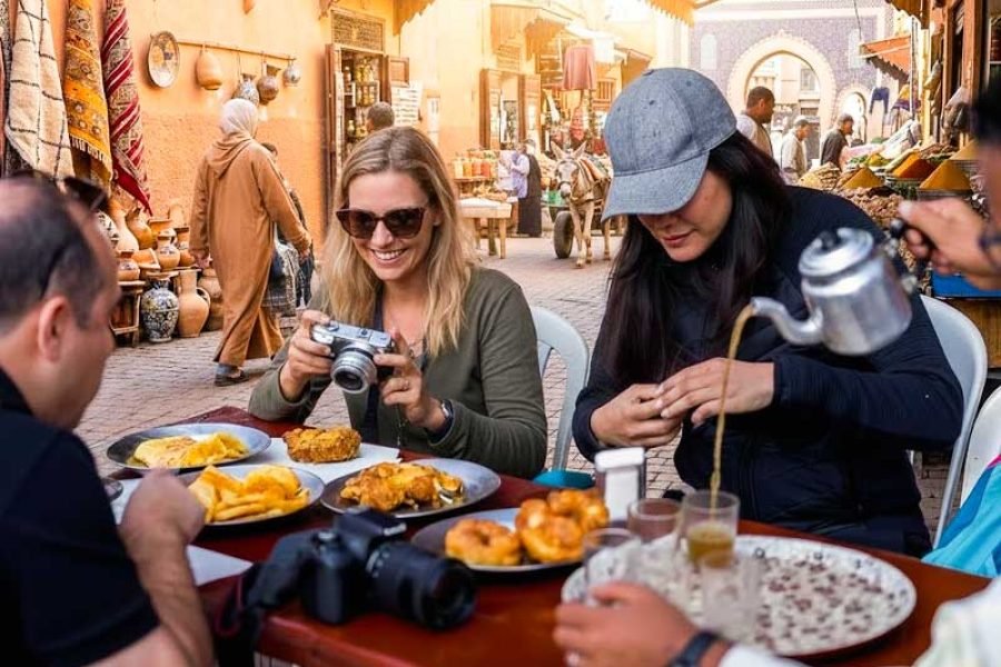 Travelers dining at an outdoor table and pouring mint tea on a Marrakech Street Food Tour.